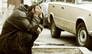 Dejected man squatting on sidwalk